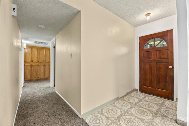 foyer with light colored carpet, baseboards, visible vents, and a textured ceiling