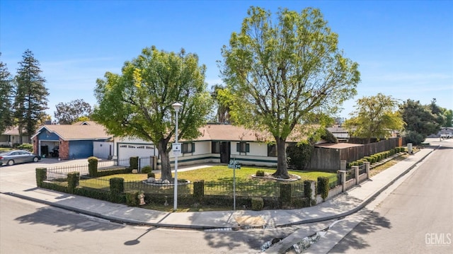 single story home with a fenced front yard, driveway, an attached garage, and a front lawn