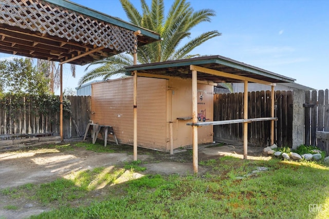 view of outbuilding with an outbuilding, a detached carport, and fence