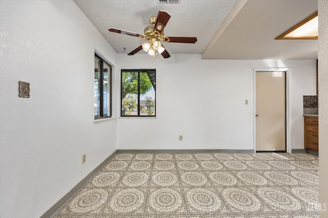 spare room featuring visible vents, baseboards, a textured ceiling, and a ceiling fan