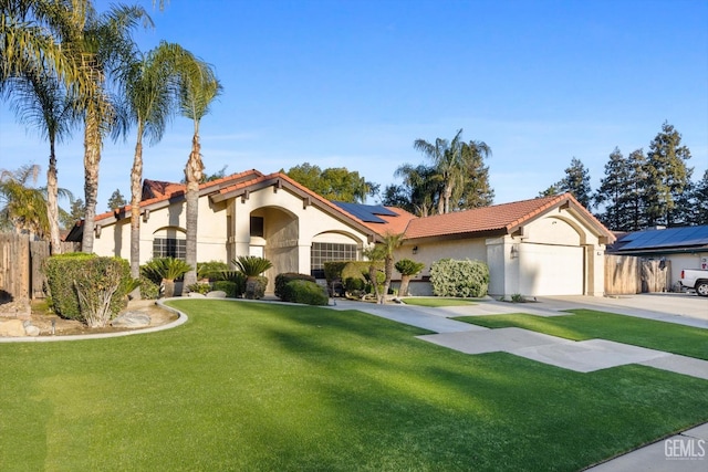 mediterranean / spanish-style home featuring a garage, solar panels, concrete driveway, a front yard, and stucco siding