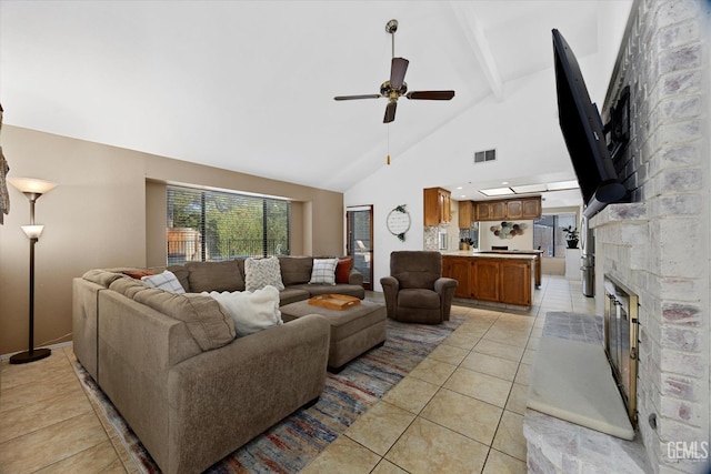 living room featuring a fireplace, visible vents, a ceiling fan, light tile patterned flooring, and high vaulted ceiling