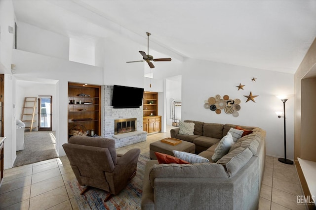 living area featuring a brick fireplace, light tile patterned flooring, ceiling fan, and beam ceiling