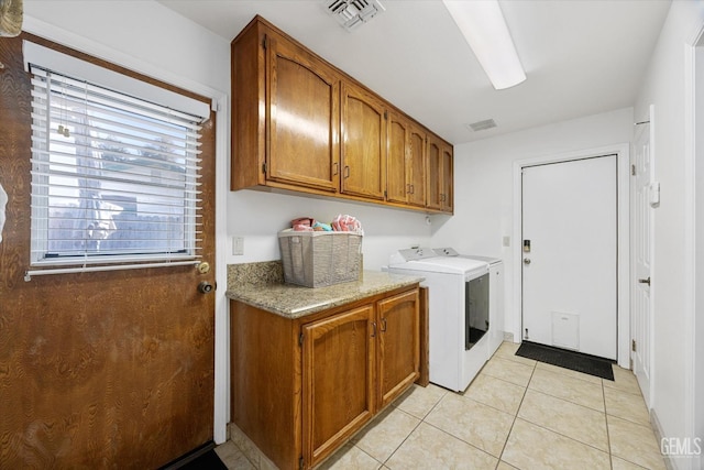 washroom with cabinet space, visible vents, washer and clothes dryer, and light tile patterned flooring