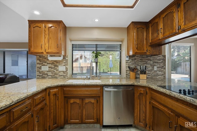 kitchen featuring plenty of natural light, a sink, stainless steel dishwasher, and light stone countertops