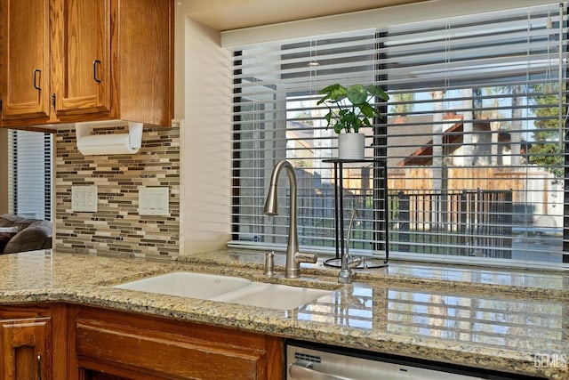 kitchen featuring plenty of natural light, brown cabinets, a sink, and backsplash