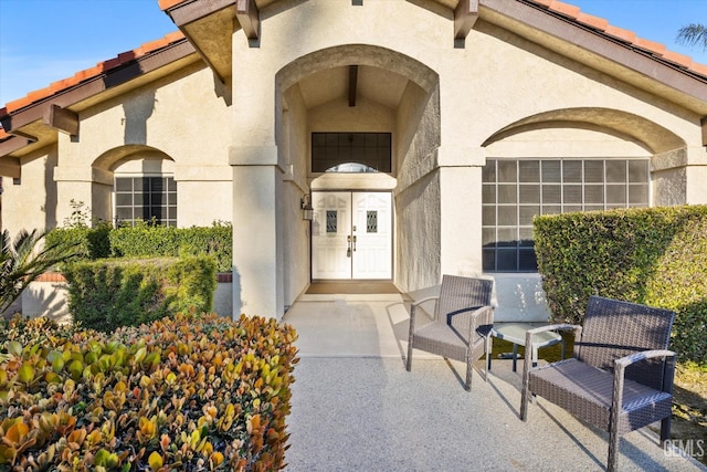 entrance to property with a tile roof and stucco siding