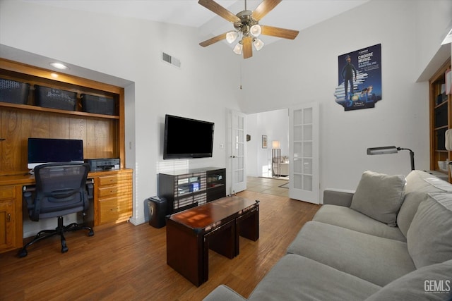 living area with ceiling fan, high vaulted ceiling, wood finished floors, visible vents, and french doors