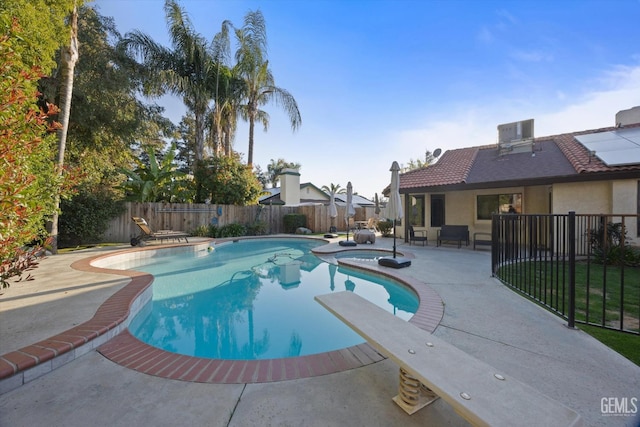 view of swimming pool with central AC unit, a fenced backyard, a patio area, a pool with connected hot tub, and a diving board