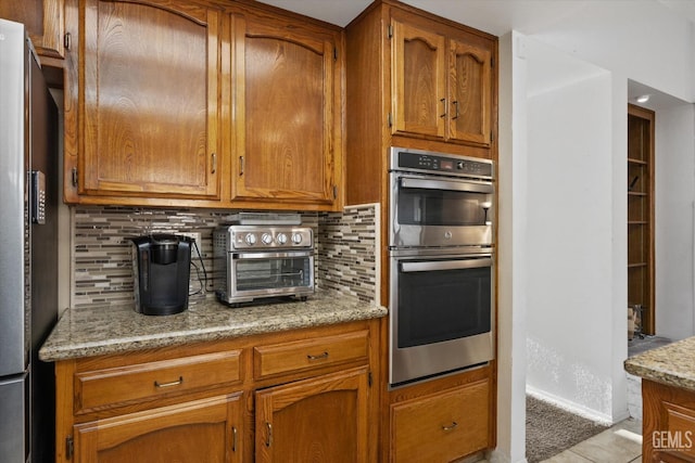 kitchen featuring stainless steel appliances, tasteful backsplash, and brown cabinets