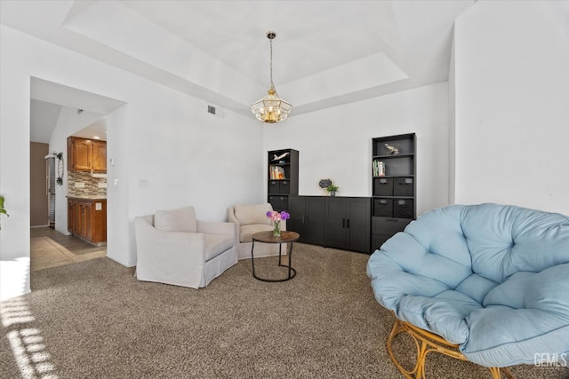 living room featuring visible vents, a tray ceiling, a chandelier, and light colored carpet