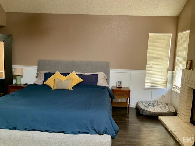 2304 Mountain Oak Rd, Bakersfield, CA 93311 - bedroom with wood finished floors, wainscoting, a fireplace, and a textured ceiling