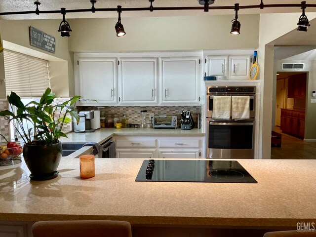 2304 Mountain Oak Rd, Bakersfield, CA 93311 - kitchen with black electric stovetop, stainless steel double oven, decorative backsplash, light countertops, and white cabinets