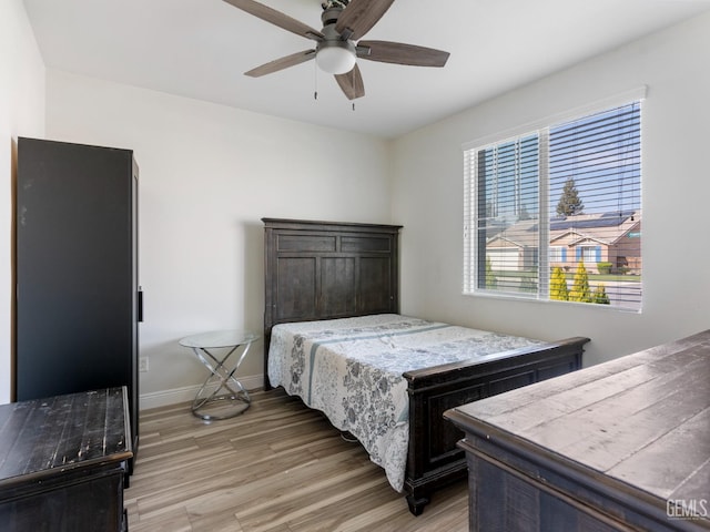 bedroom featuring light wood finished floors, baseboards, and a ceiling fan