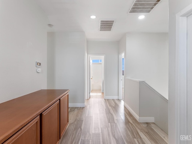 corridor with light wood-style floors, baseboards, and visible vents