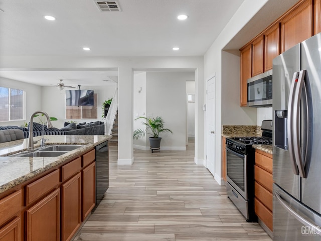 kitchen featuring a sink, visible vents, open floor plan, appliances with stainless steel finishes, and light stone countertops