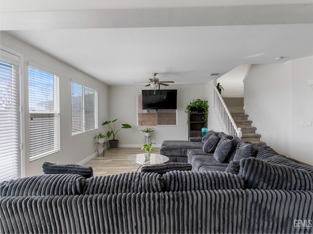 living area featuring baseboards, stairs, a ceiling fan, and wood finished floors