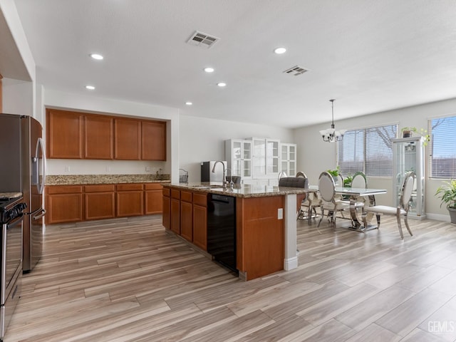 kitchen with hanging light fixtures, appliances with stainless steel finishes, an island with sink, and visible vents