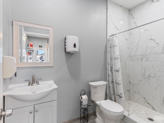 bathroom featuring toilet, a marble finish shower, vanity, and baseboards