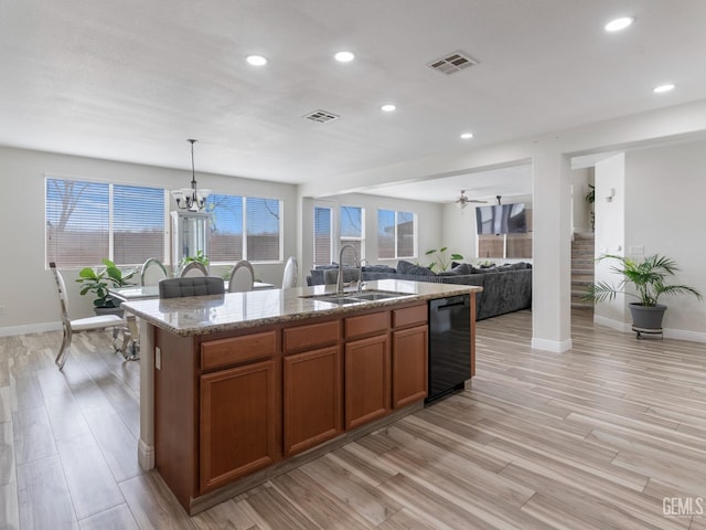 kitchen featuring an island with sink, a sink, visible vents, and pendant lighting