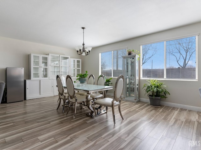 dining room featuring baseboards, light wood finished floors, and an inviting chandelier