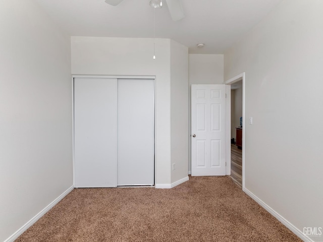 unfurnished bedroom featuring carpet floors, a closet, baseboards, and a ceiling fan