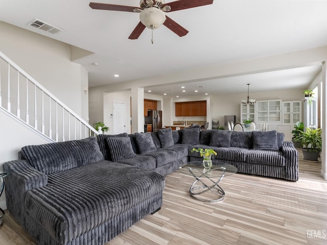 living area featuring light wood-style floors, stairway, and visible vents