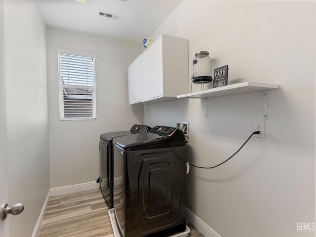 laundry area with light wood finished floors, cabinet space, visible vents, baseboards, and washing machine and dryer