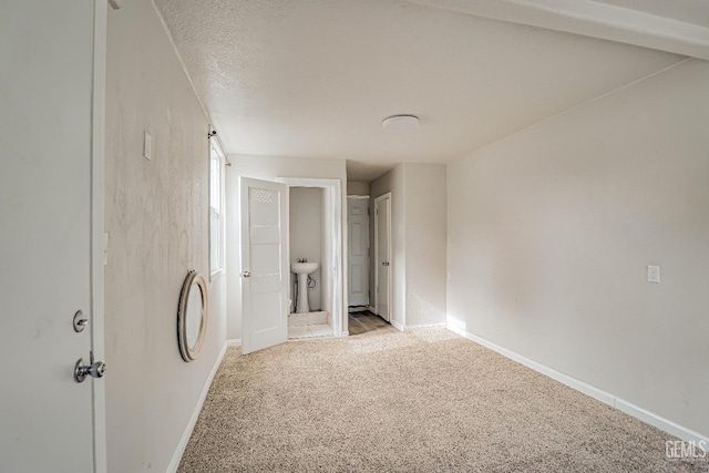 unfurnished bedroom with light carpet, ensuite bathroom, baseboards, and a sink