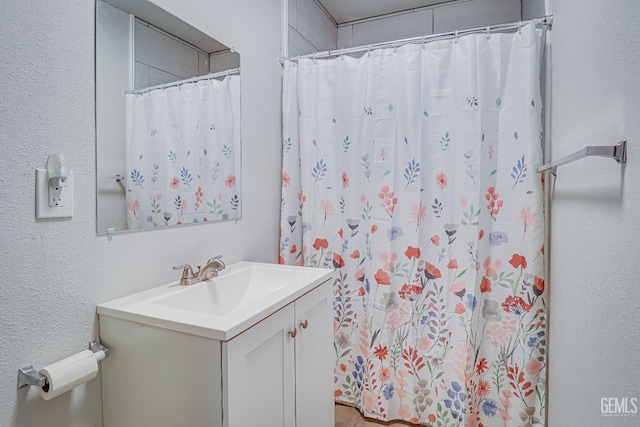 full bath featuring a textured wall, vanity, and a shower with shower curtain