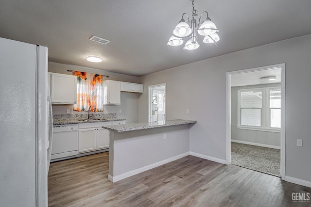 kitchen with visible vents, a sink, white appliances, a peninsula, and white cabinetry
