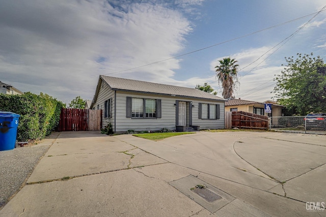 bungalow-style home featuring concrete driveway and fence