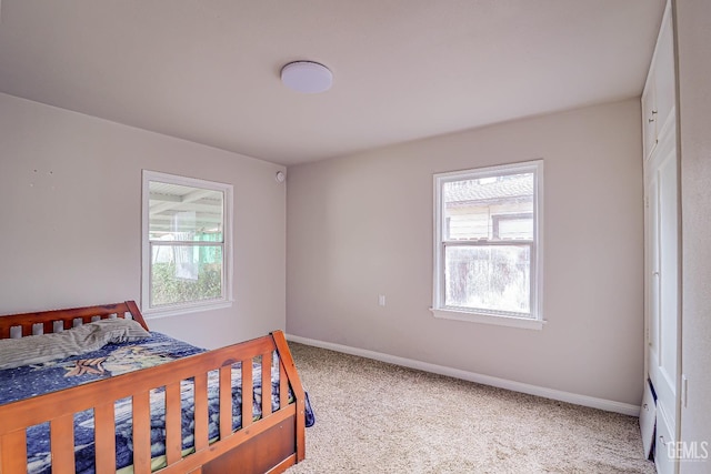bedroom with light colored carpet, baseboards, and multiple windows