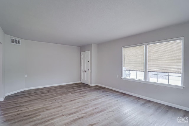 unfurnished room with wood finished floors, visible vents, and baseboards