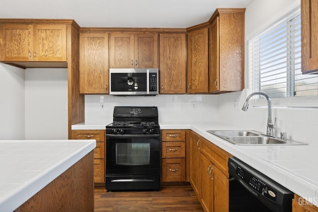 kitchen with sink, tile countertops, dark hardwood / wood-style floors, and black appliances