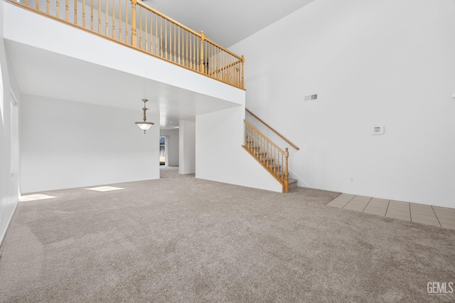 unfurnished living room with a high ceiling and carpet flooring