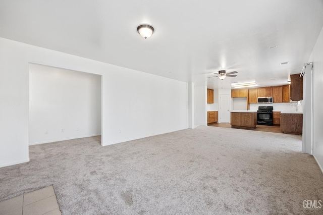 unfurnished living room featuring light carpet and ceiling fan