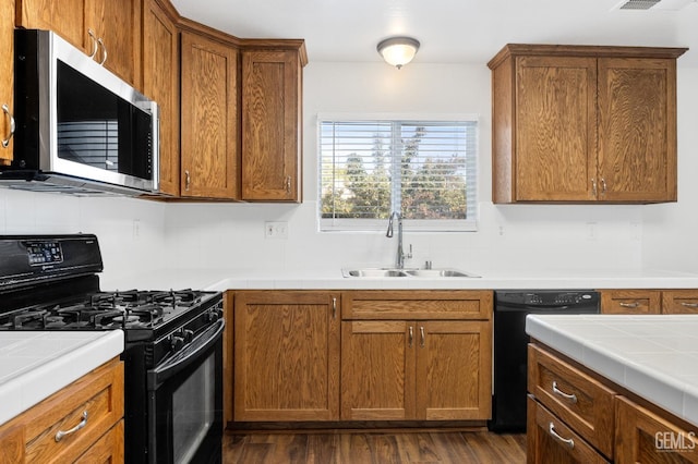 kitchen with sink, tile countertops, dark hardwood / wood-style floors, decorative backsplash, and black appliances