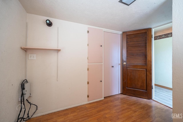 spare room featuring baseboards, a textured ceiling, and wood finished floors