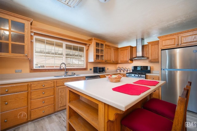 kitchen featuring a kitchen island, light countertops, appliances with stainless steel finishes, wall chimney exhaust hood, and a sink