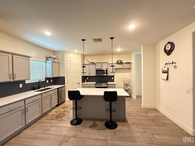 6009 Cardano Ave, Bakersfield, CA 93313 - kitchen with stainless steel appliances, gray cabinets, light wood-type flooring, a breakfast bar area, and light countertops