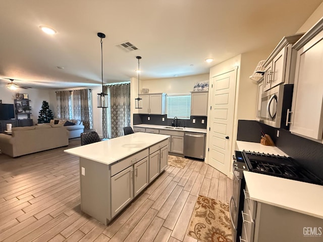 6009 Cardano Ave, Bakersfield, CA 93313 - kitchen with appliances with stainless steel finishes, light wood-style floors, gray cabinetry, open floor plan, and light countertops