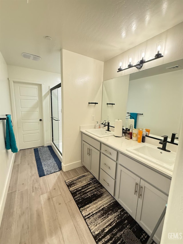 6009 Cardano Ave, Bakersfield, CA 93313 - bathroom with wood finished floors, double vanity, and a shower stall