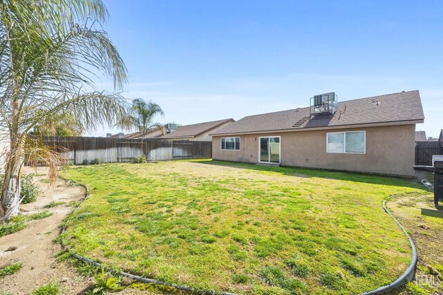 rear view of house with central AC unit and a lawn