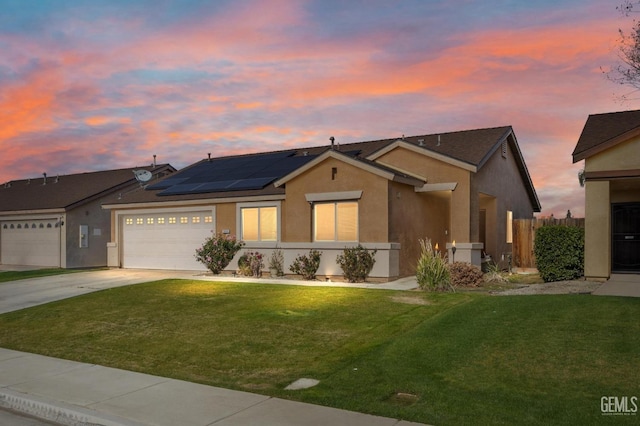 view of front facade with a garage, a yard, and solar panels