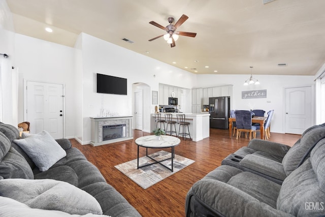 living room with high vaulted ceiling, ceiling fan with notable chandelier, and dark hardwood / wood-style flooring