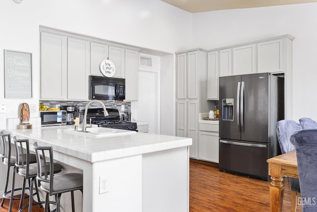 kitchen featuring lofted ceiling, tasteful backsplash, tile countertops, stainless steel fridge with ice dispenser, and stove