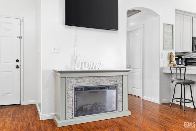 unfurnished living room featuring a stone fireplace and dark hardwood / wood-style flooring