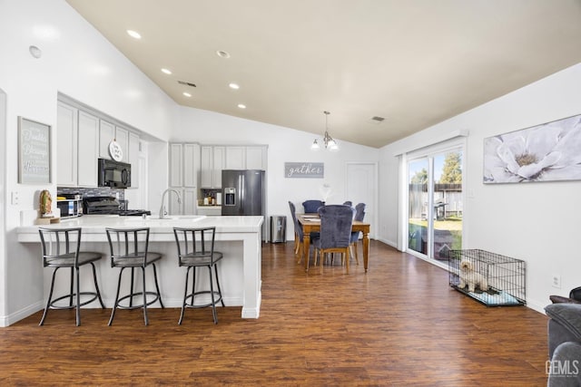 kitchen featuring a breakfast bar, dark hardwood / wood-style floors, stainless steel fridge, range, and kitchen peninsula