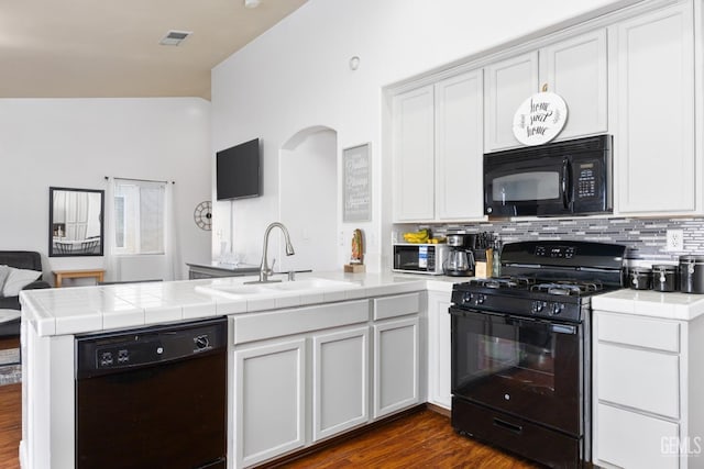 kitchen with sink, black appliances, white cabinets, tile countertops, and kitchen peninsula